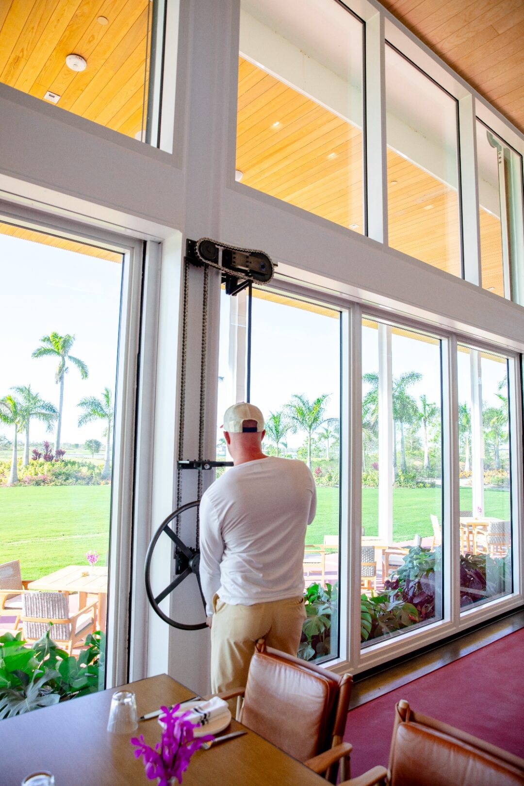 Open glass panel with chain-and-sprocket lift mechanism looking out to the fairway