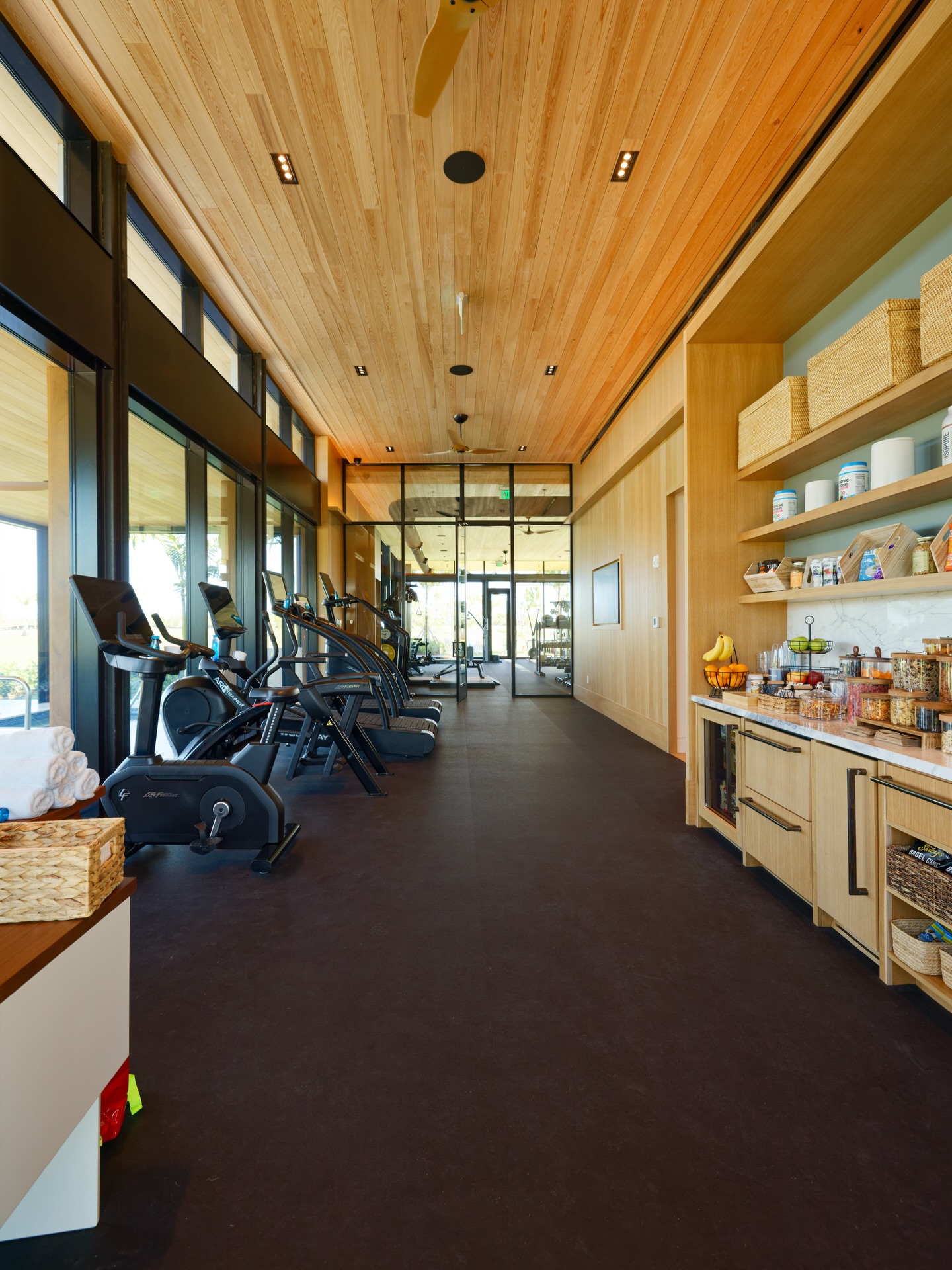 Atlantic Fields Performance Center cardio floor &mdash; floor-to-ceiling storefront glazing runs the full length of the wall, looking out to the courtyard