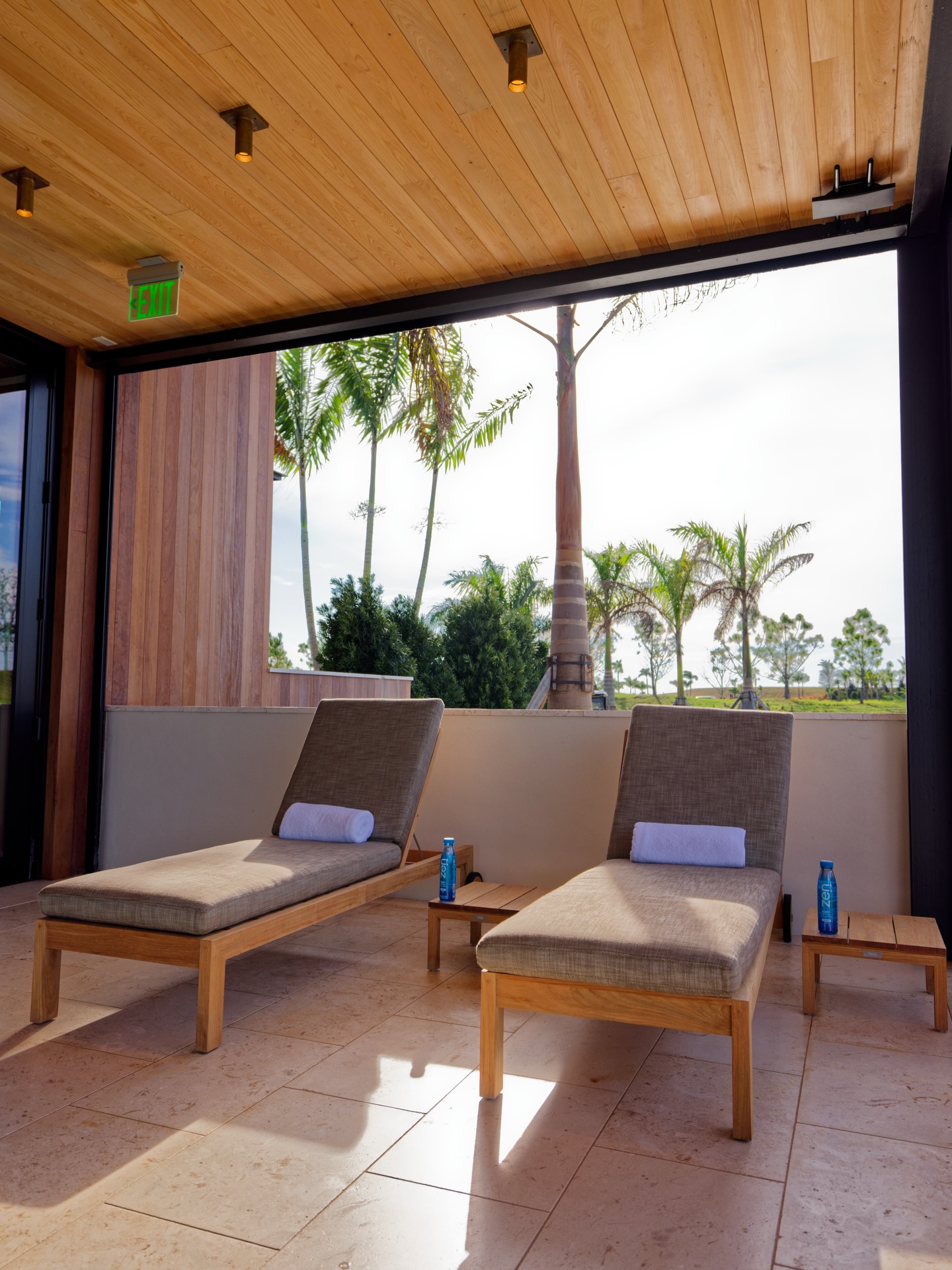 Atlantic Fields Performance Center recovery terrace &mdash; Euro-Wall multi-slide opens the wall to a palm-tree courtyard with chaise lounges