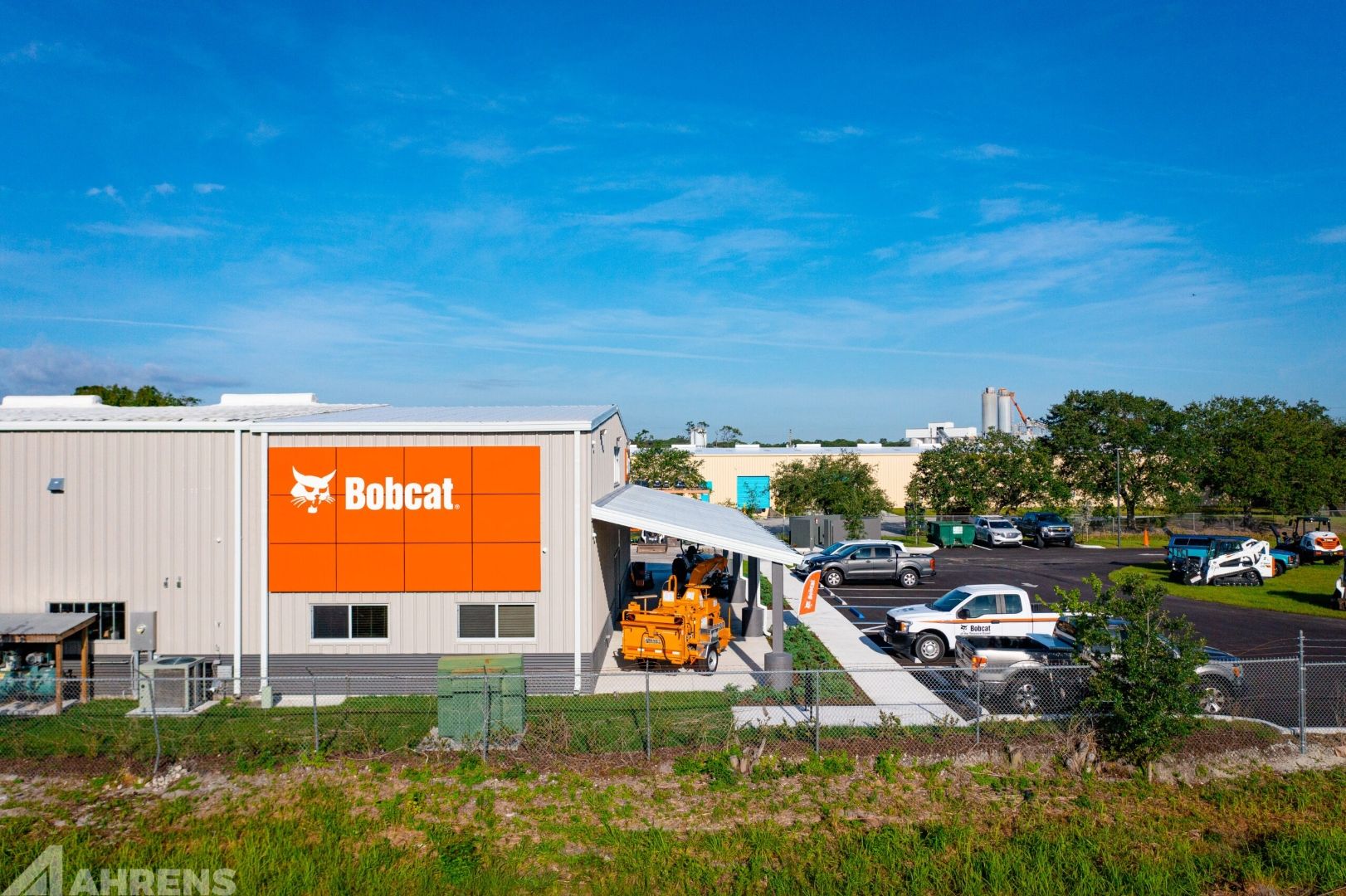Bobcat of the Treasure Coast side exterior — large orange Bobcat branded wall panel, covered canopy, commercial window band visible above