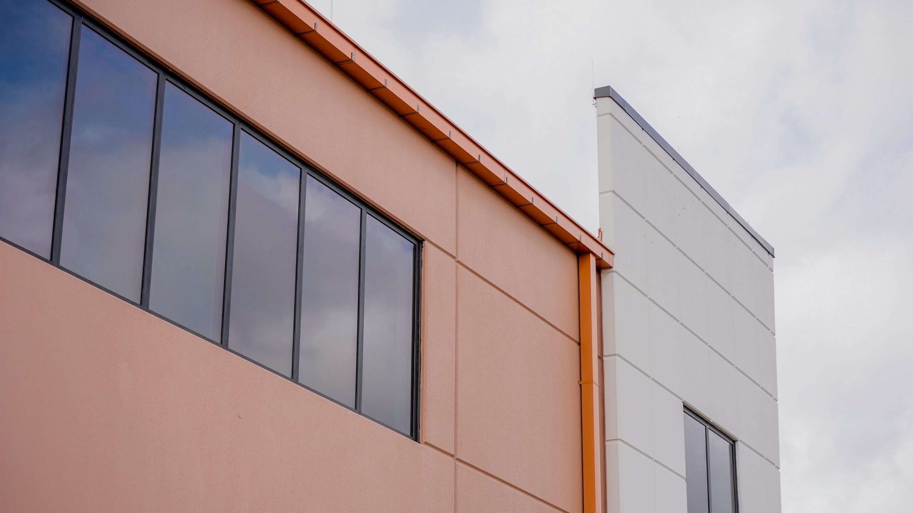 Two-story facade corner with horizontal aluminum storefront band on the office wing, Haines City EOC