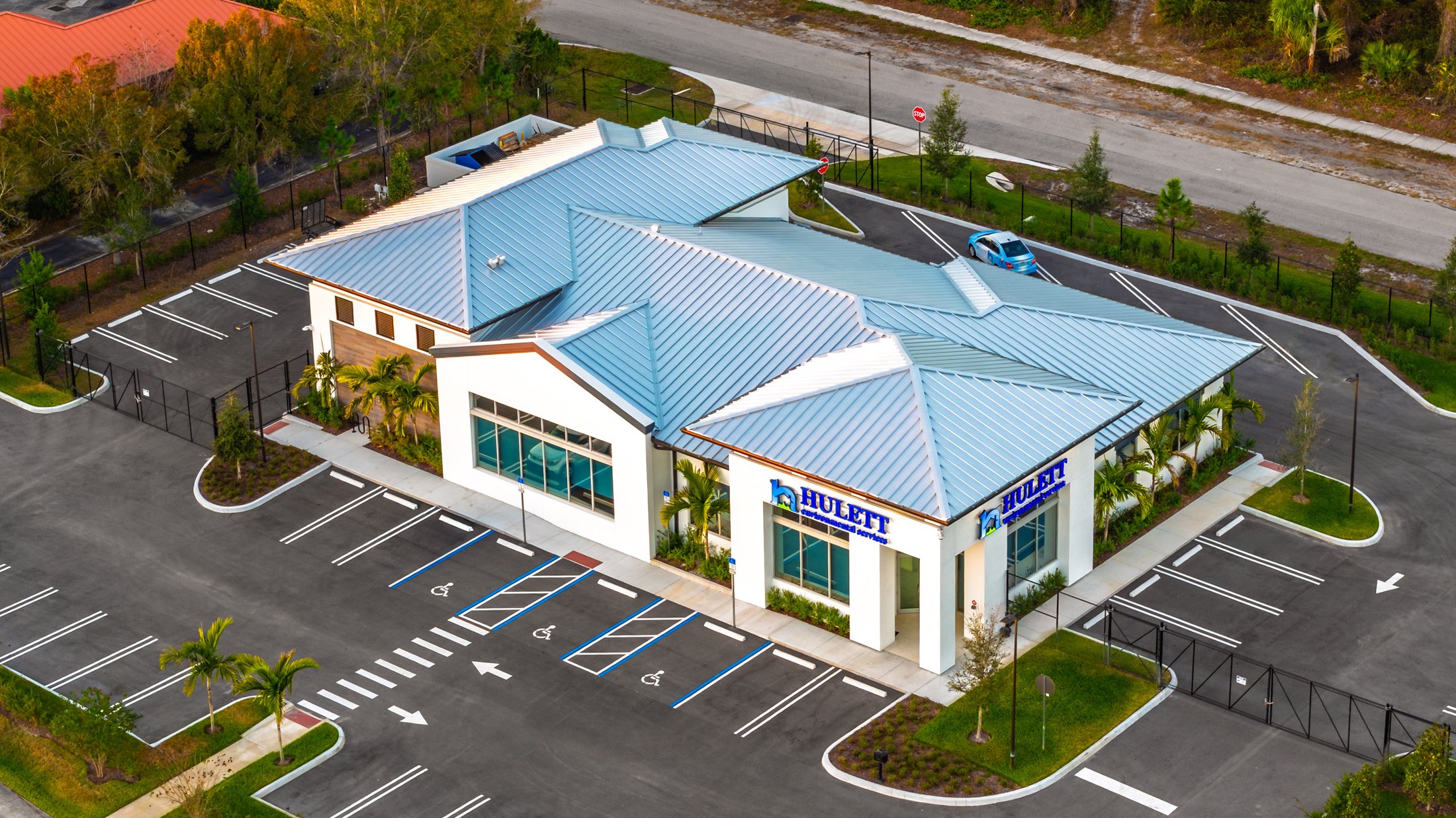 Hulett Environmental aerial — corner perspective showing front and side elevations of the headquarters, parking lot, surrounding Treasure Coast roads