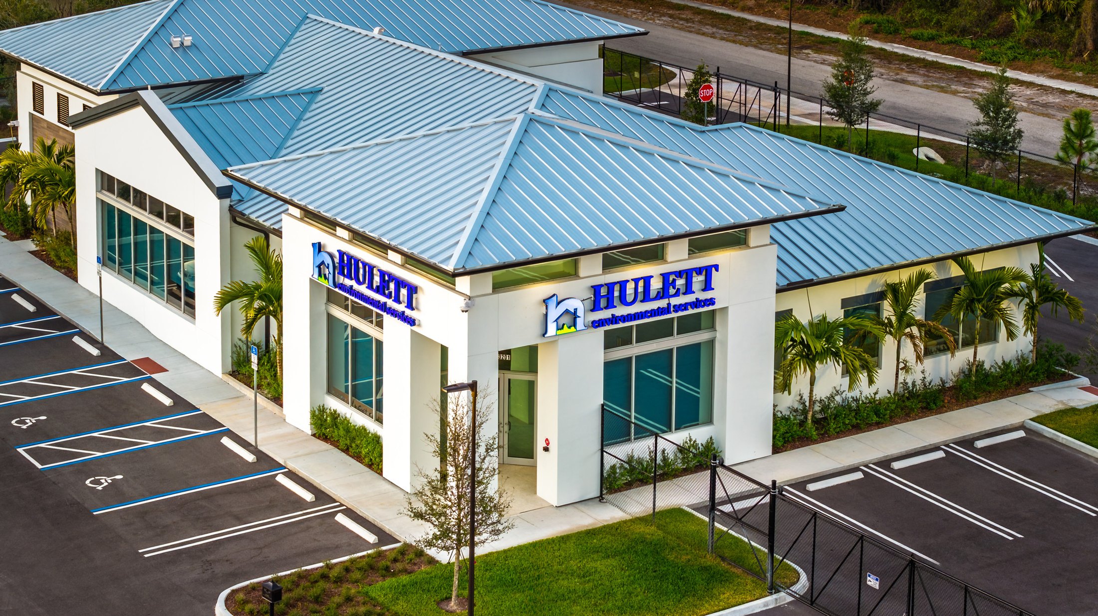 Hulett Environmental — close aerial of the front entry showing the ESWindows two-story storefront, Hulett Environmental dark blue signage, and front landscaping