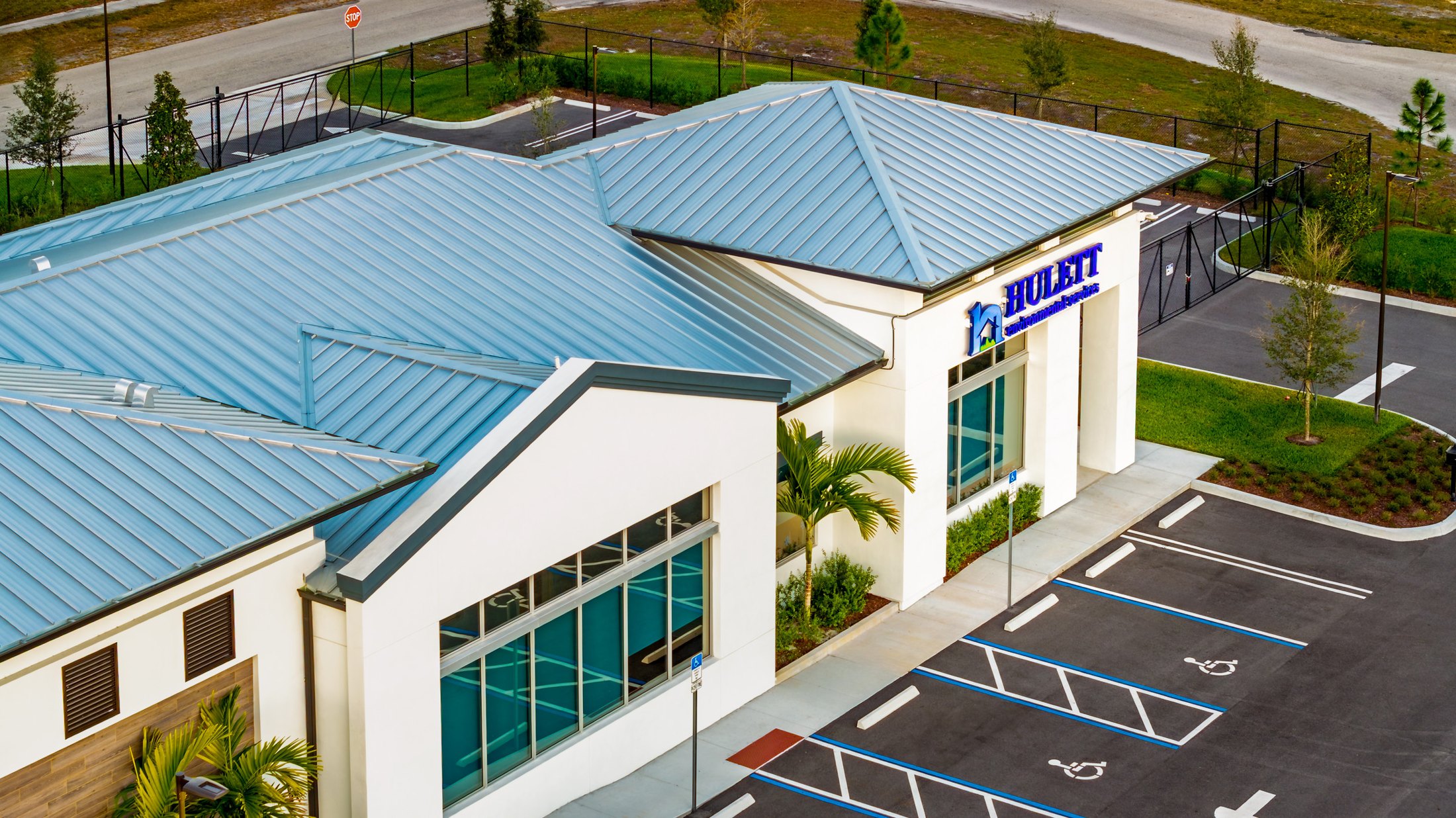 Hulett Environmental Port St. Lucie aerial — side elevation showing the building's wing extending toward palm landscaping, full ESWindows window package visible on both stories