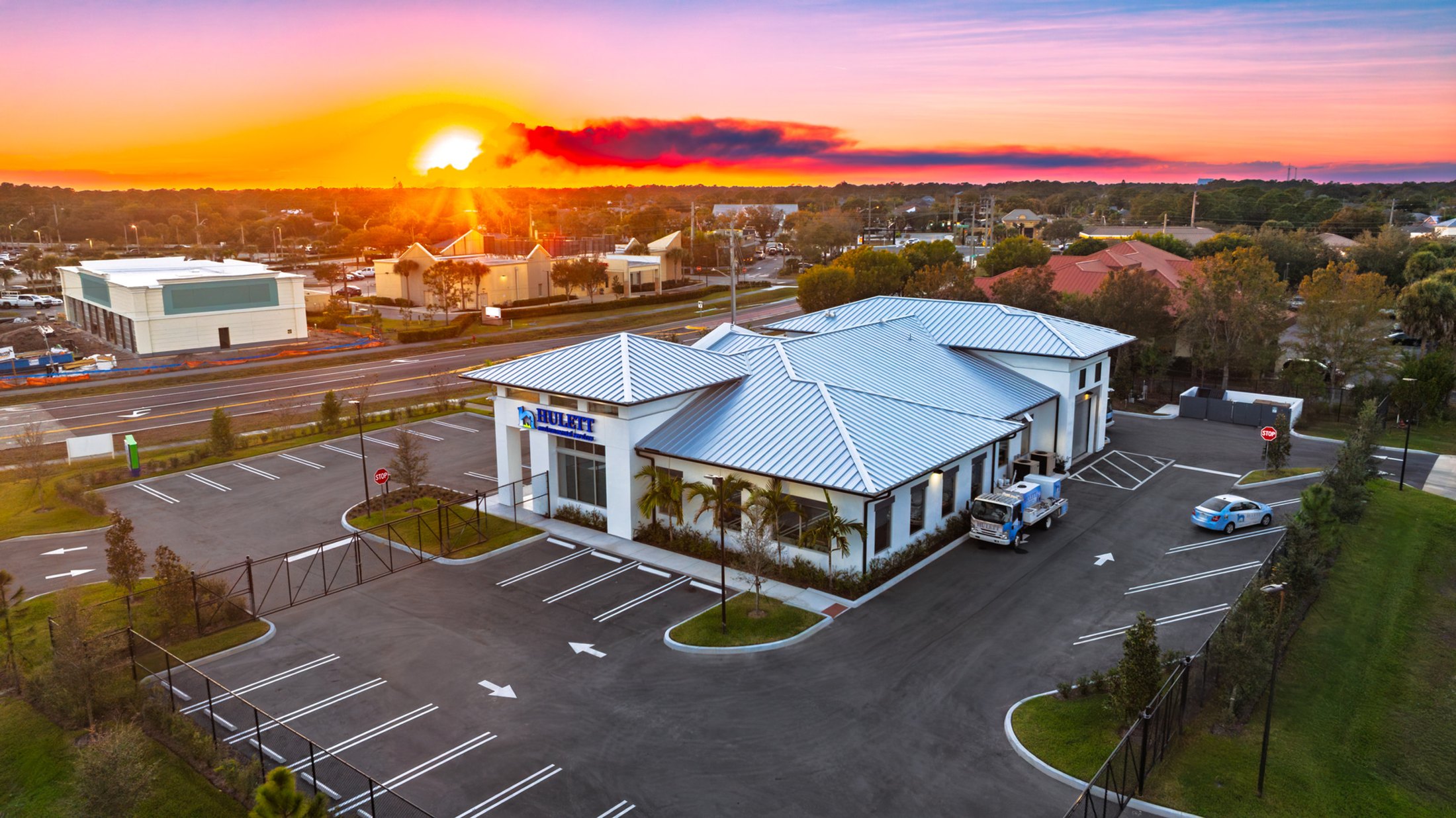 Hulett Environmental Port St. Lucie at sunrise — aerial view from the rear of the building with the sun rising behind, ESWindows clerestory band visible on the upper facade