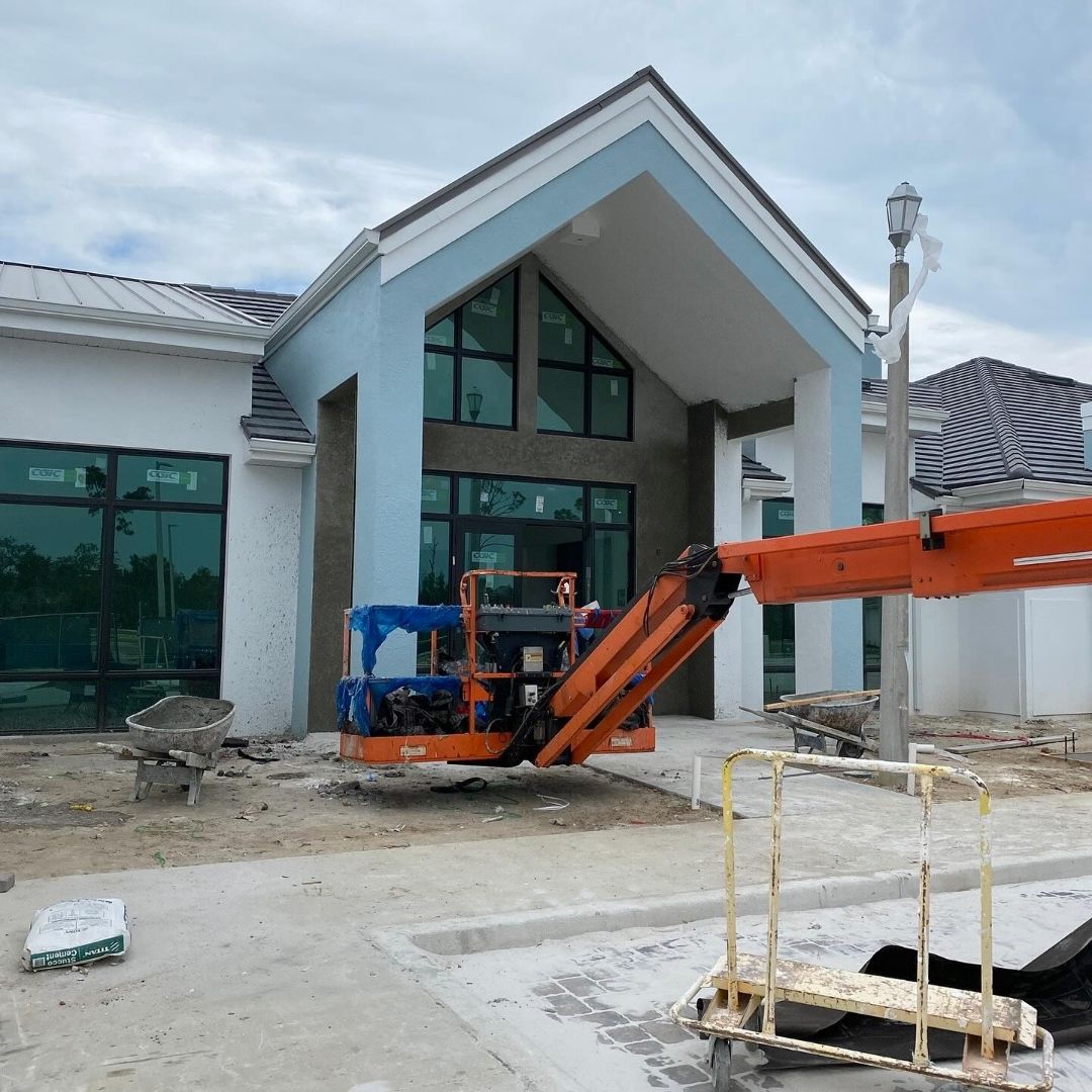 Imperial Crossings clubhouse entry during construction Bonita Springs FL — gabled glass facade with floor-to-ceiling storefront windows, ACG commercial glazing