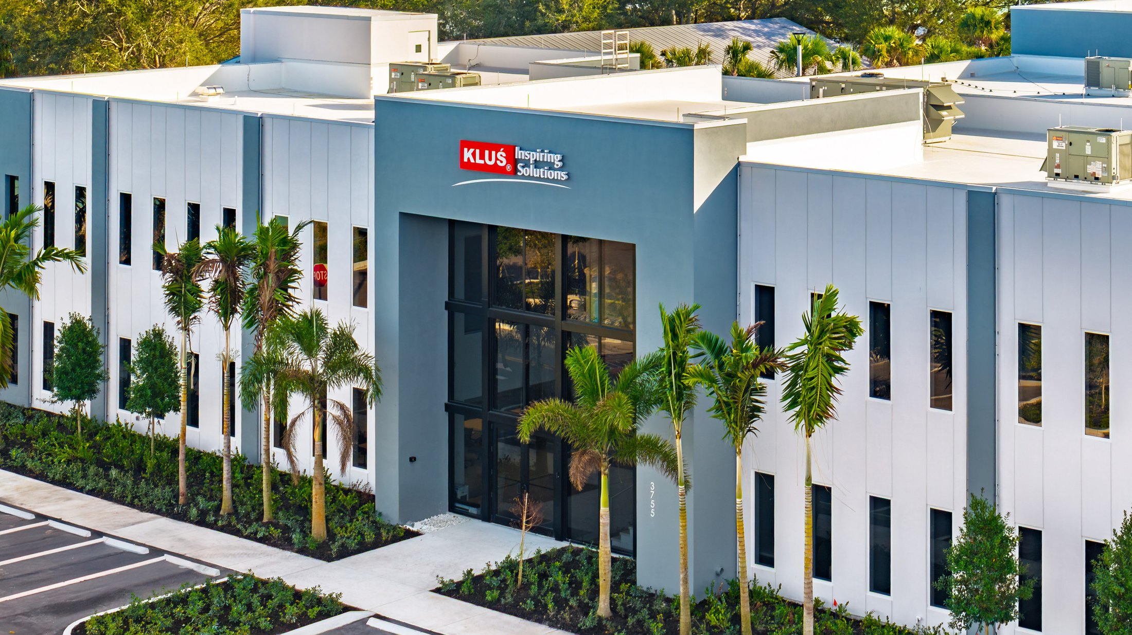 KLUS Lighting Vero Beach — entry tower from a side angle with the larger warehouse mass extending behind, ESWindows storefront fully glazed