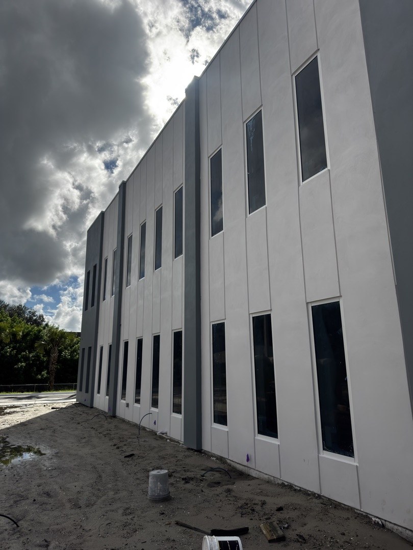 KLUS Lighting Vero Beach — side facade with punched commercial windows installed across both stories, white tilt-up panels with grey banding, ESWindows impact-rated framing
