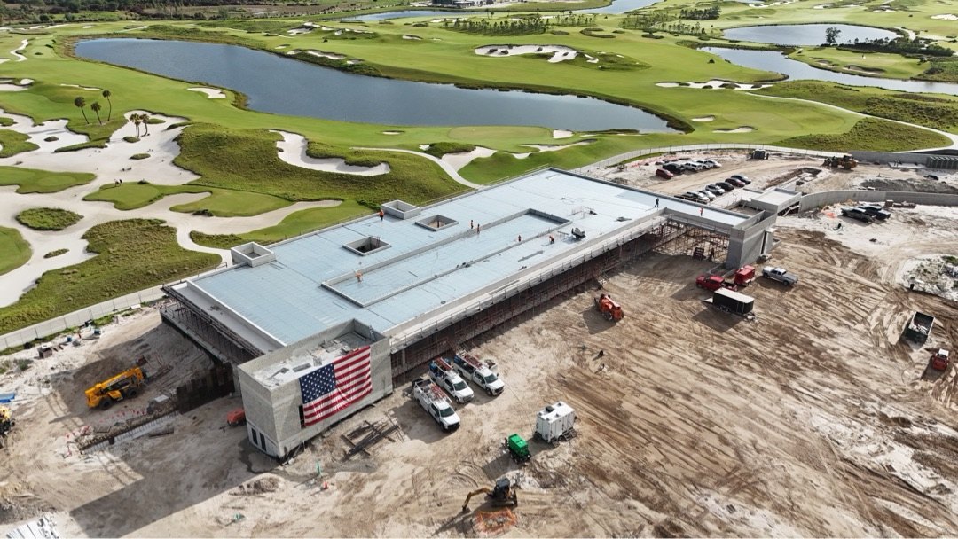 Panther National Clubhouse — aerial view with American flag mounted on the structure during construction, ACG service fleet on site