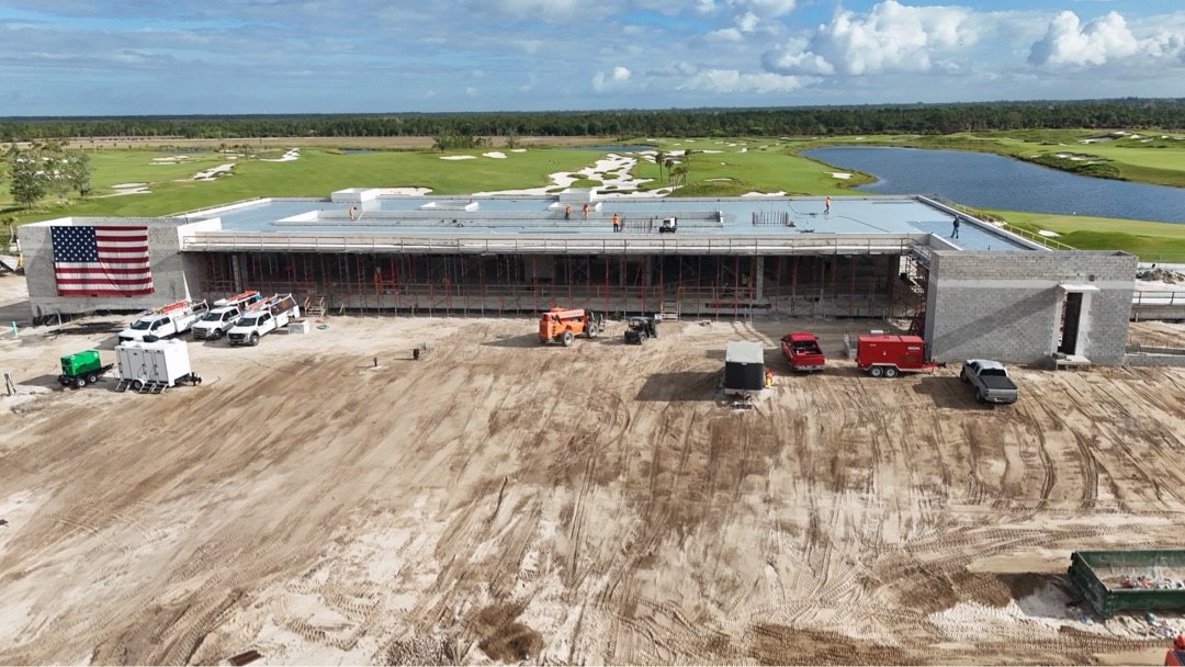 Panther National Clubhouse — aerial view from golf course side showing long glazing elevation facing the course and water hazards