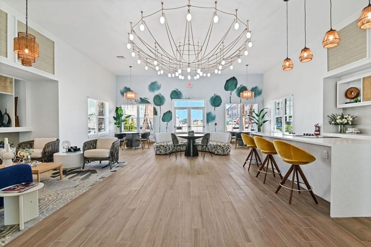Tradewinds Hobe Sound clubhouse interior with double-height ceiling, chandelier, and floor-to-ceiling storefront windows